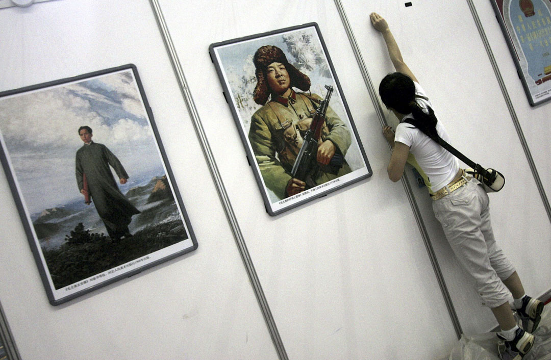 2006年深圳國際文化產業博覽會上，一名工人在展覽區佈展，當中有雷鋒及已故領導人毛澤東的海報。