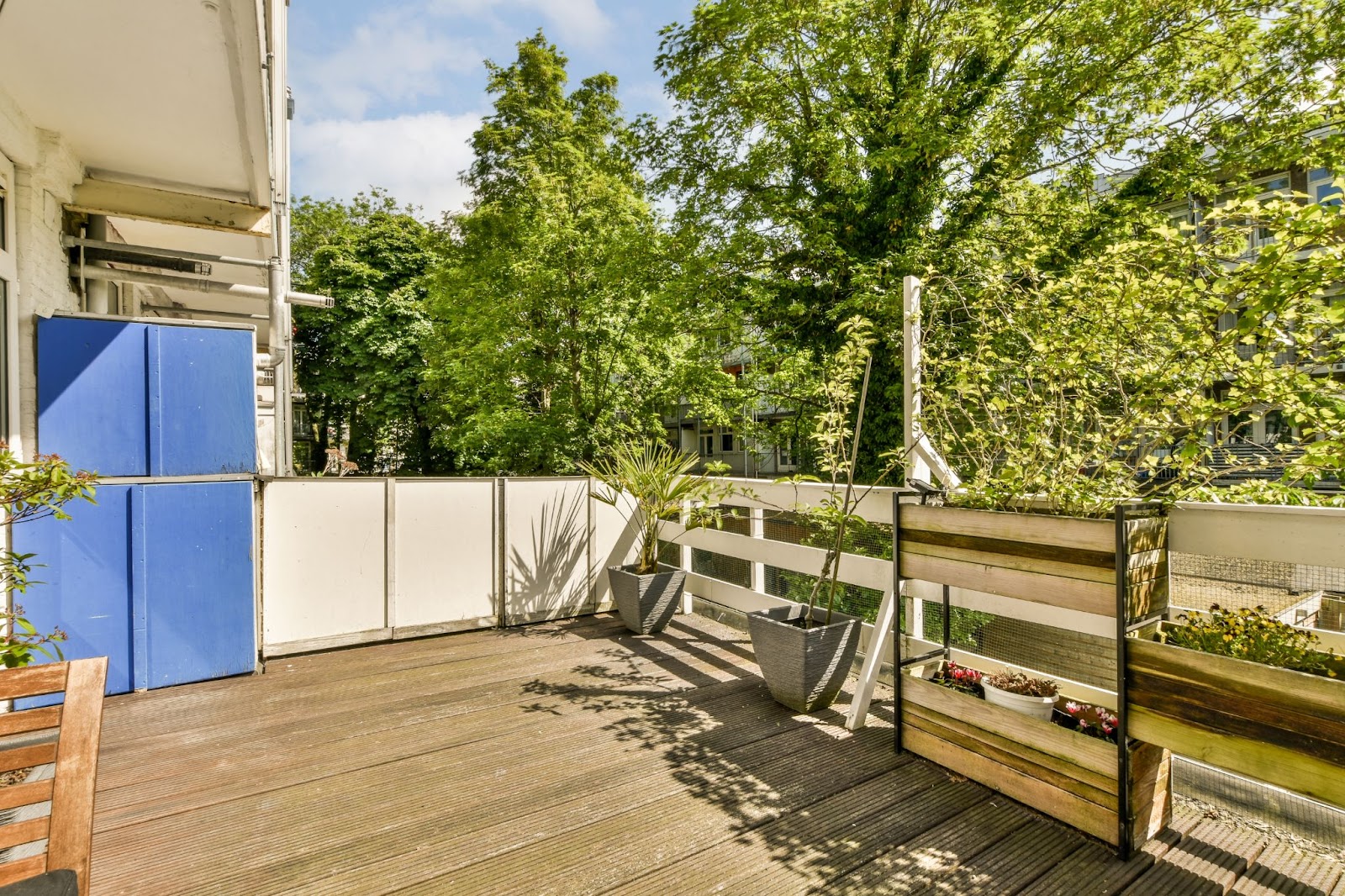 A wooden deck with wood railings and potted plants.