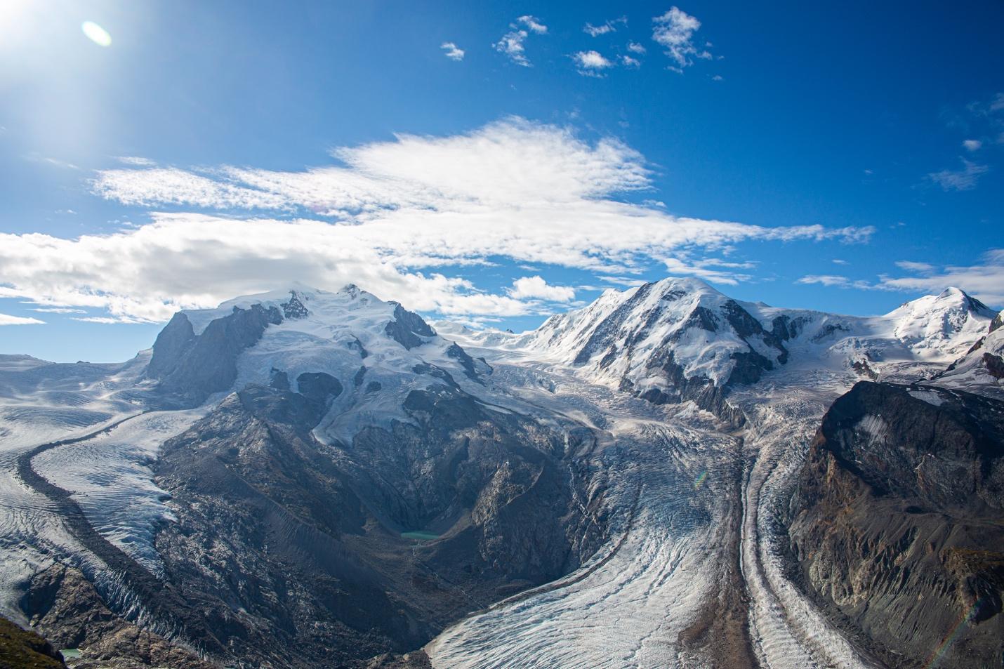 A snowy mountain range with blue sky

Description automatically generated