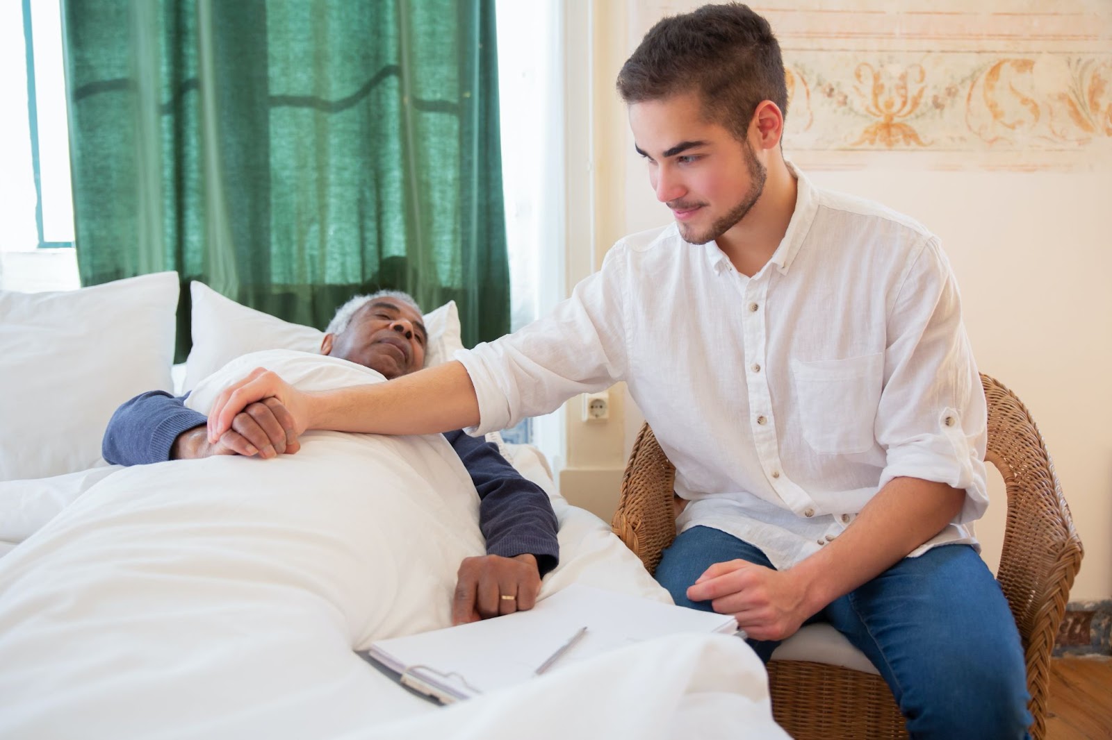 A caregiver placing his hand on a senior's hands 