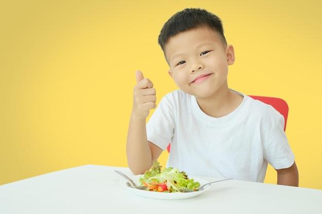 Premium Photo | Asian 5 years old kindergarten boy child eating salad show thumb  up kid enjoying vegetarian food with copy space healthy food healthy life  style isolated on yellow background with