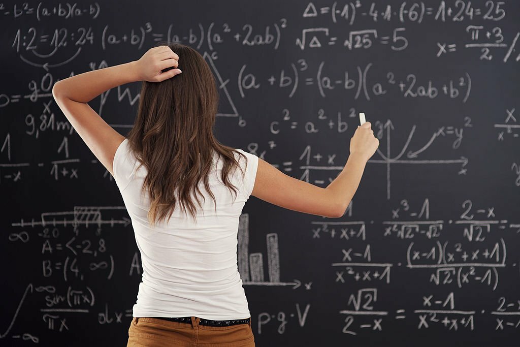 teacher solving a math question on a blackboard