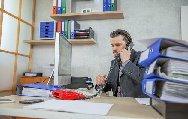 Young businessman working from his office while talking on the phone