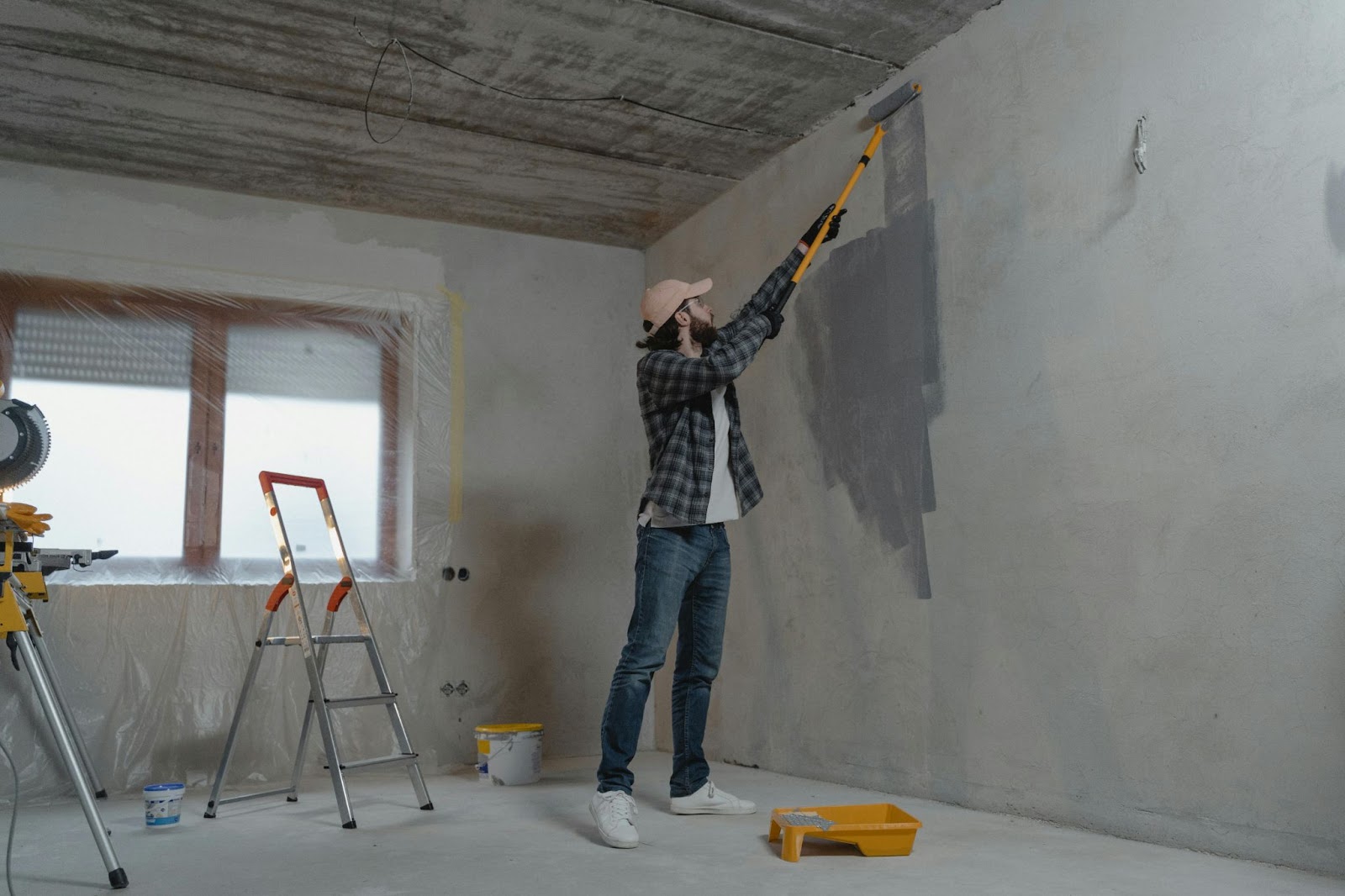 A guy paints over a wall as part of a home renovation project
