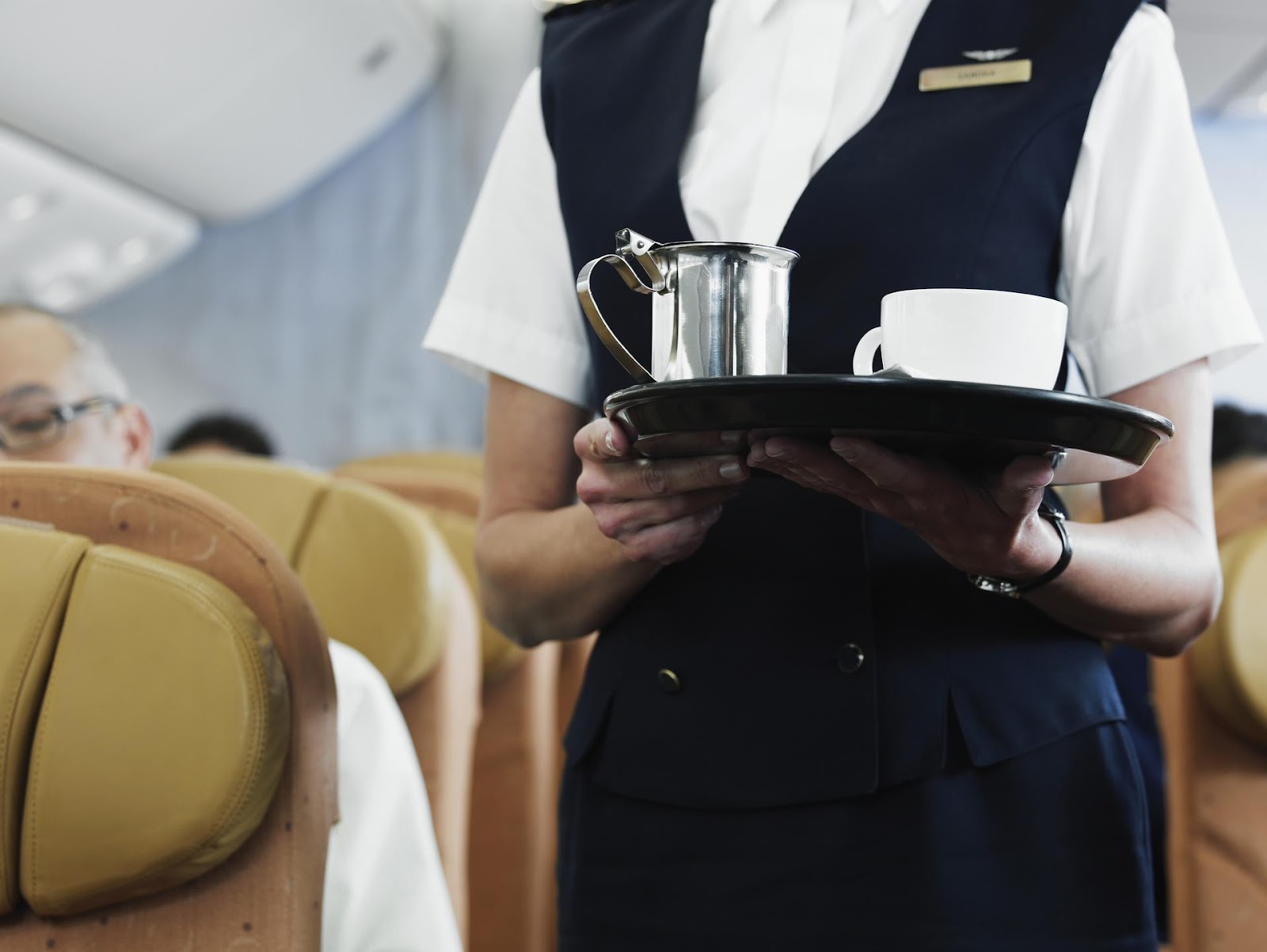 Ein Flugbegleiter hält ein Tablett mit Kaffee und einer Tasse.