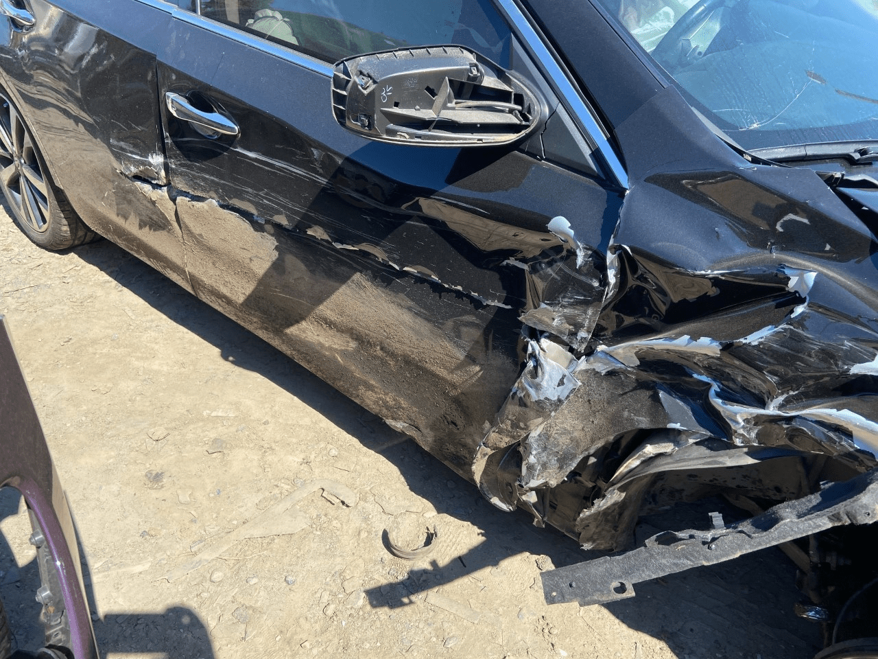 Daños en el panel lateral de un vehículo de motor negro después de un accidente automovilístico en Charlotte.