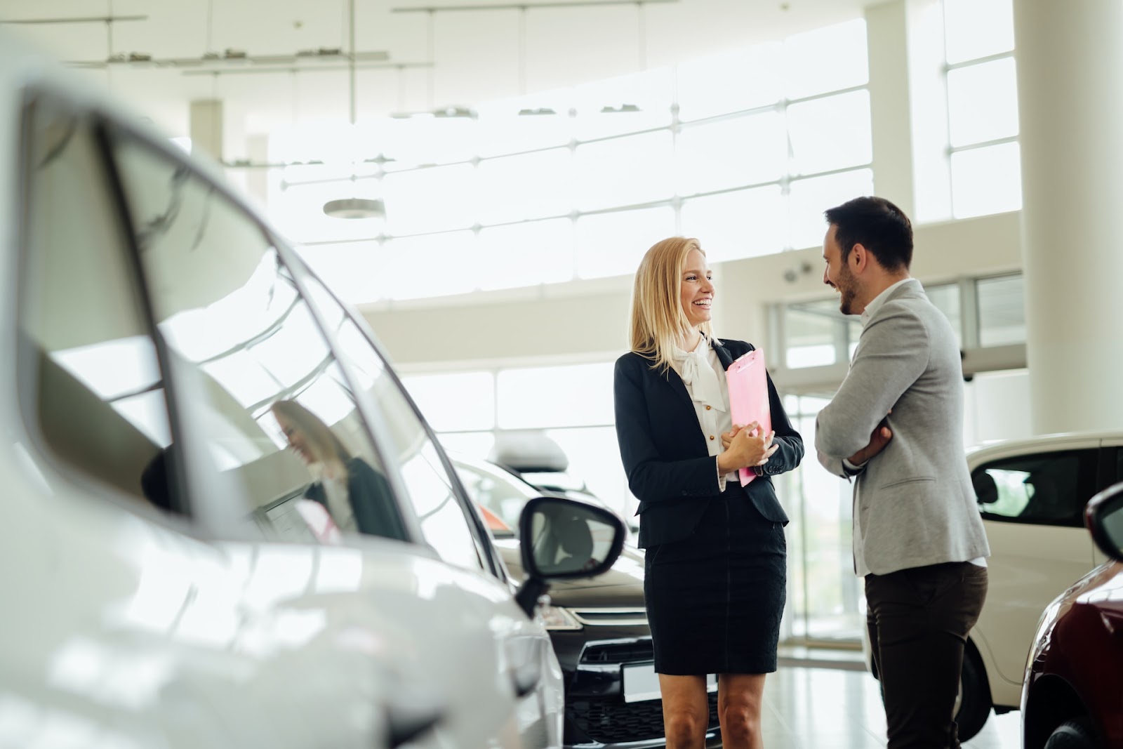 A car salesperson and a man chat in a car showroom
