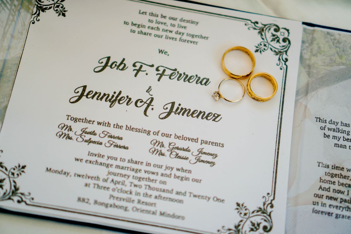 招待状の上に置かれた結婚指輪と婚約指輪