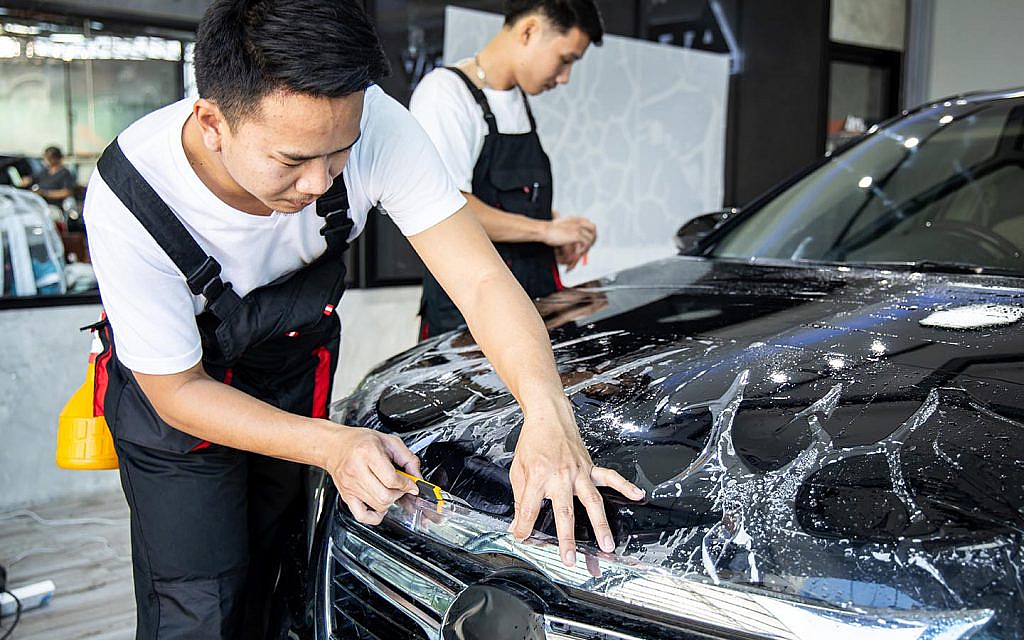 Auto expert placing paint protection film over a car