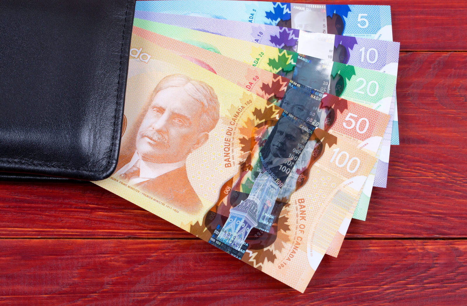 Canadian bills beside a black wallet.