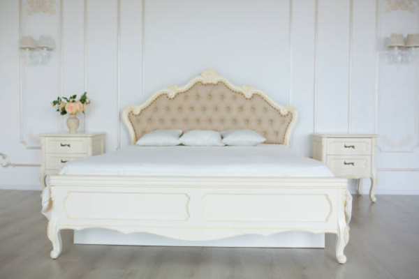 White ornate bed frame in a white bedroom.