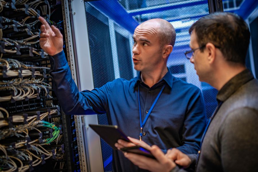 Two men looking at cables in a server room.