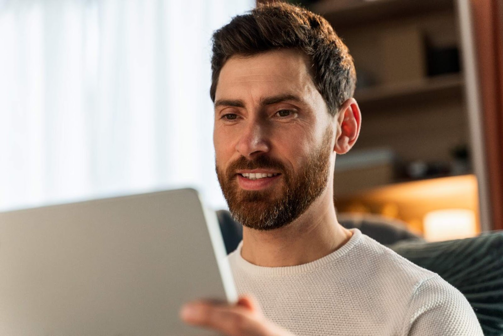 young-man-sitting-on-bed-and-looking-at-ipad