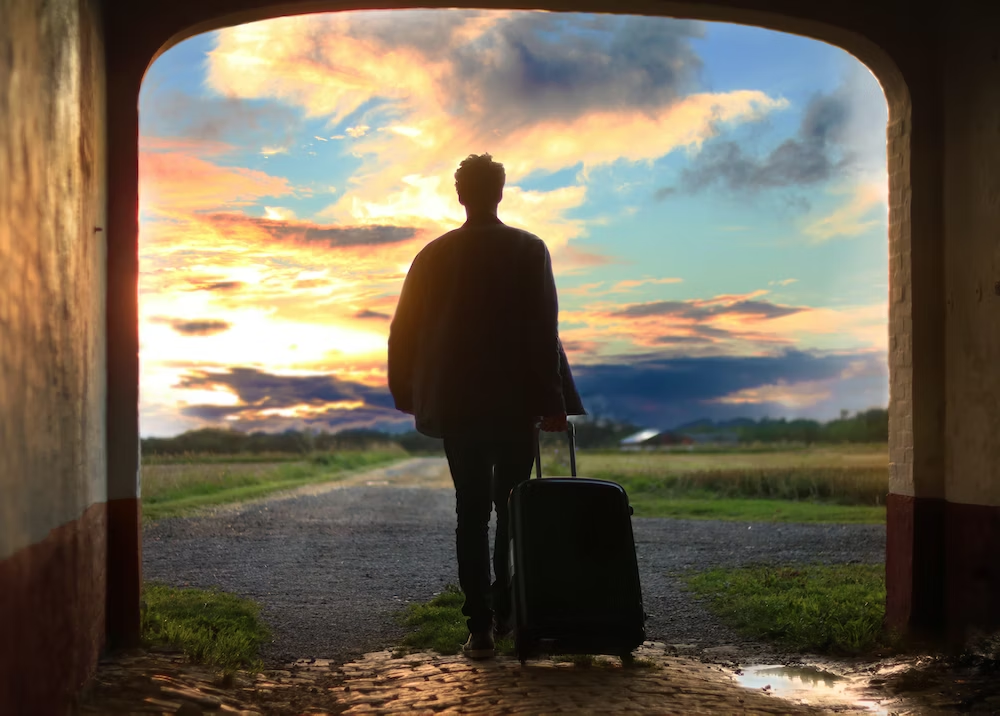A Person Moving Towards The Horizon With A Suitcase in Hand