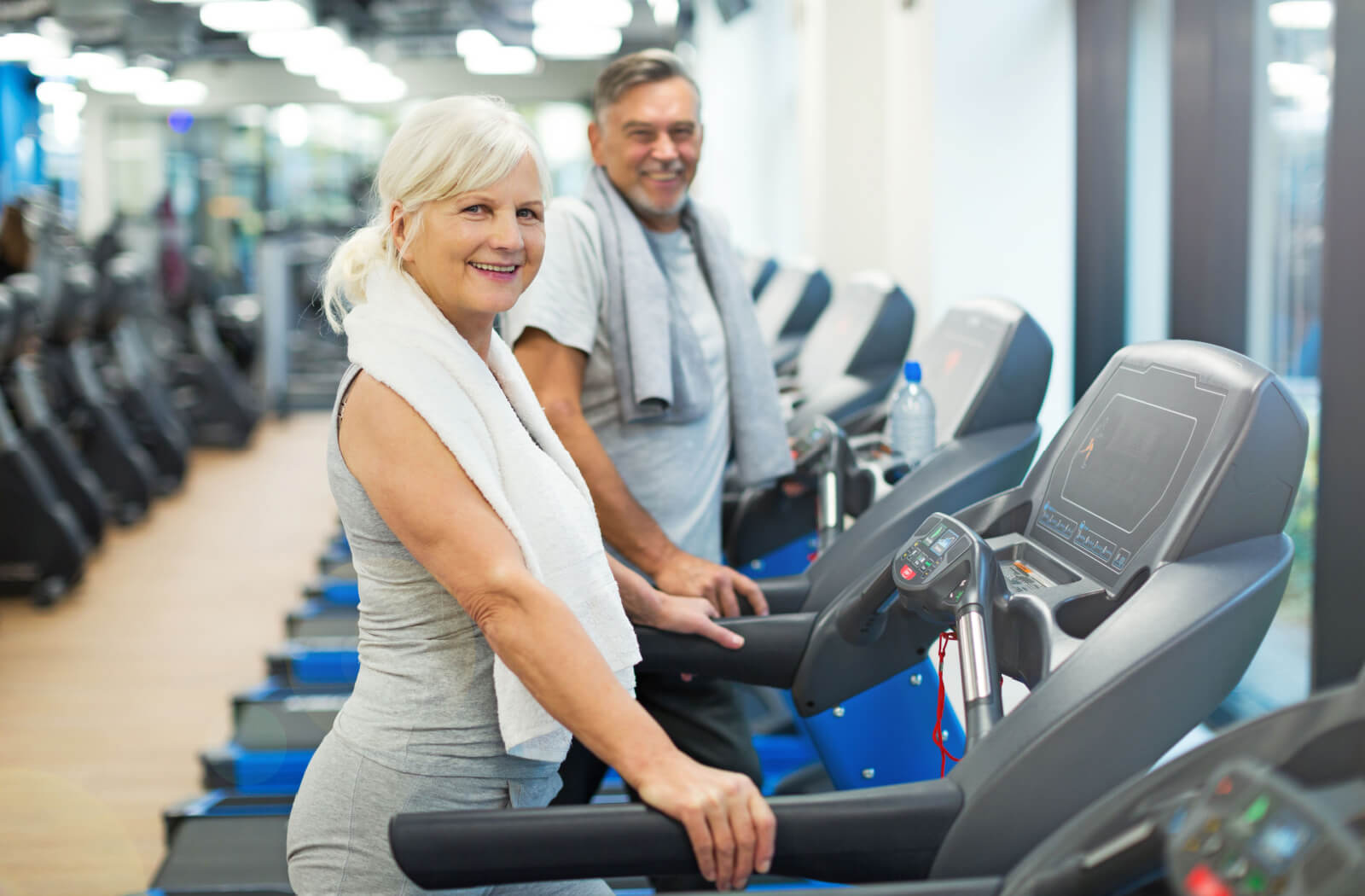 An older adult couple both using a treadmill as part of their regular exercise routine.
