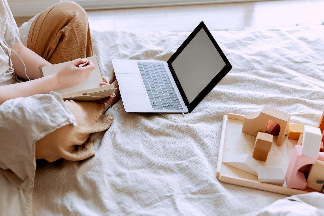 Free Crop woman using laptop on bed Stock Photo