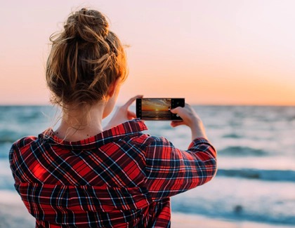 Woman taking photo of sunset