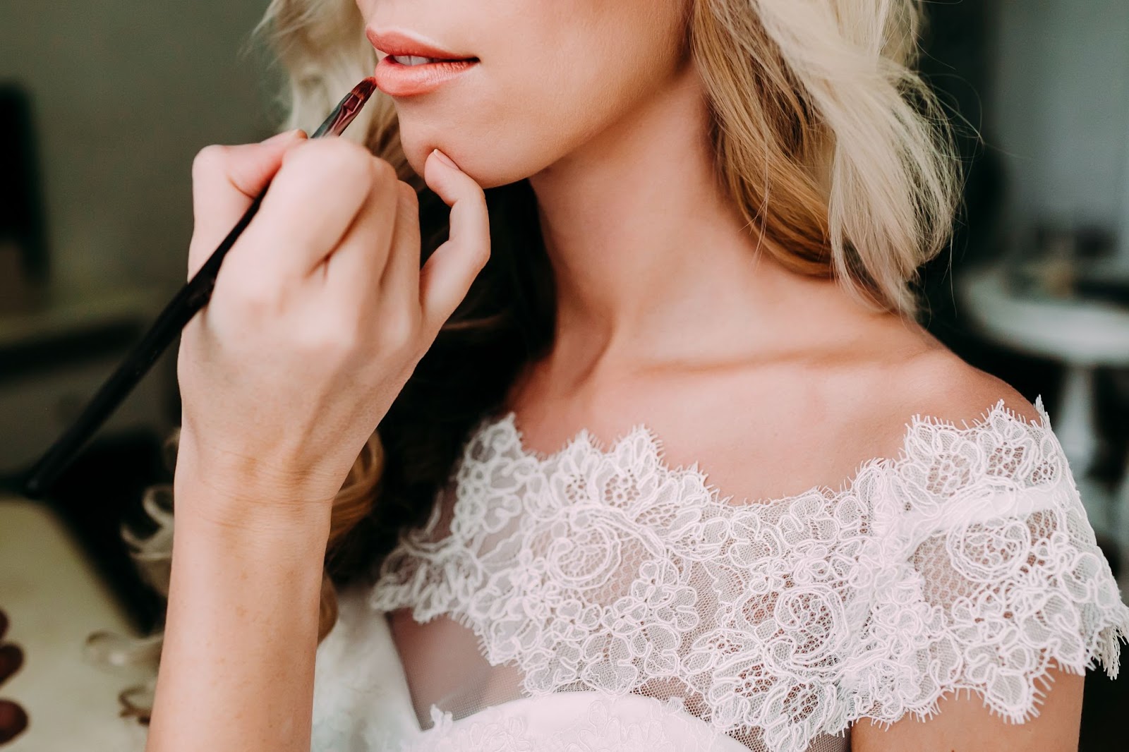 Close-up of a makeup artists applying lipstick on a bride