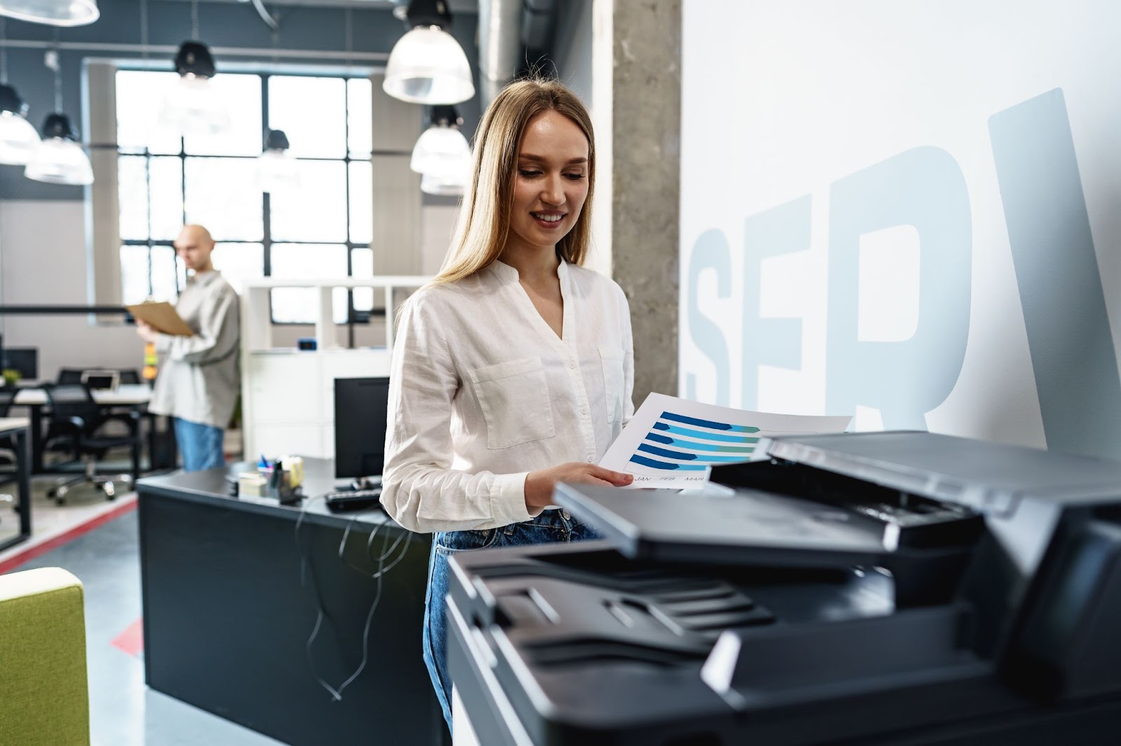 (Alt text: A young employee using Eco-friendly copiers in Florida/Alabama office setting.)