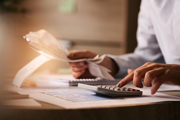 Free photo closeup of economist using calculator while going through bills and taxes in the office