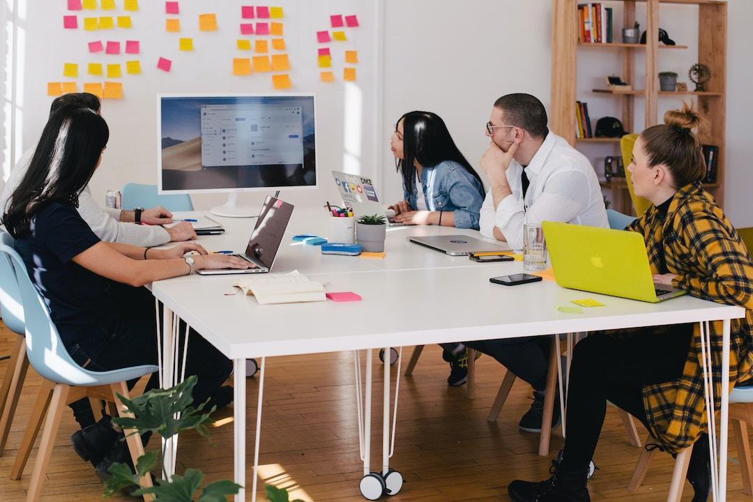 A team sitting at a white table with laptops looking at revenue leakage on a computer screen