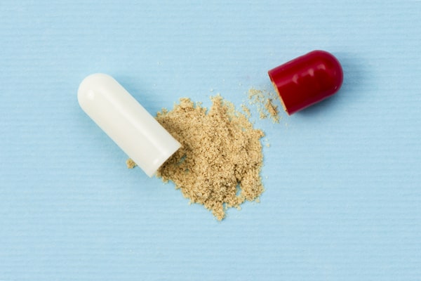 A capsule split open with the powder spilling on the table