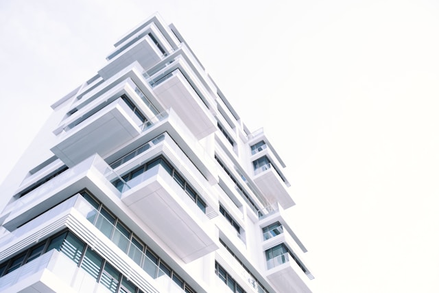 A white building with blue glass windows with a lot of projections in fromt of a clear white sky