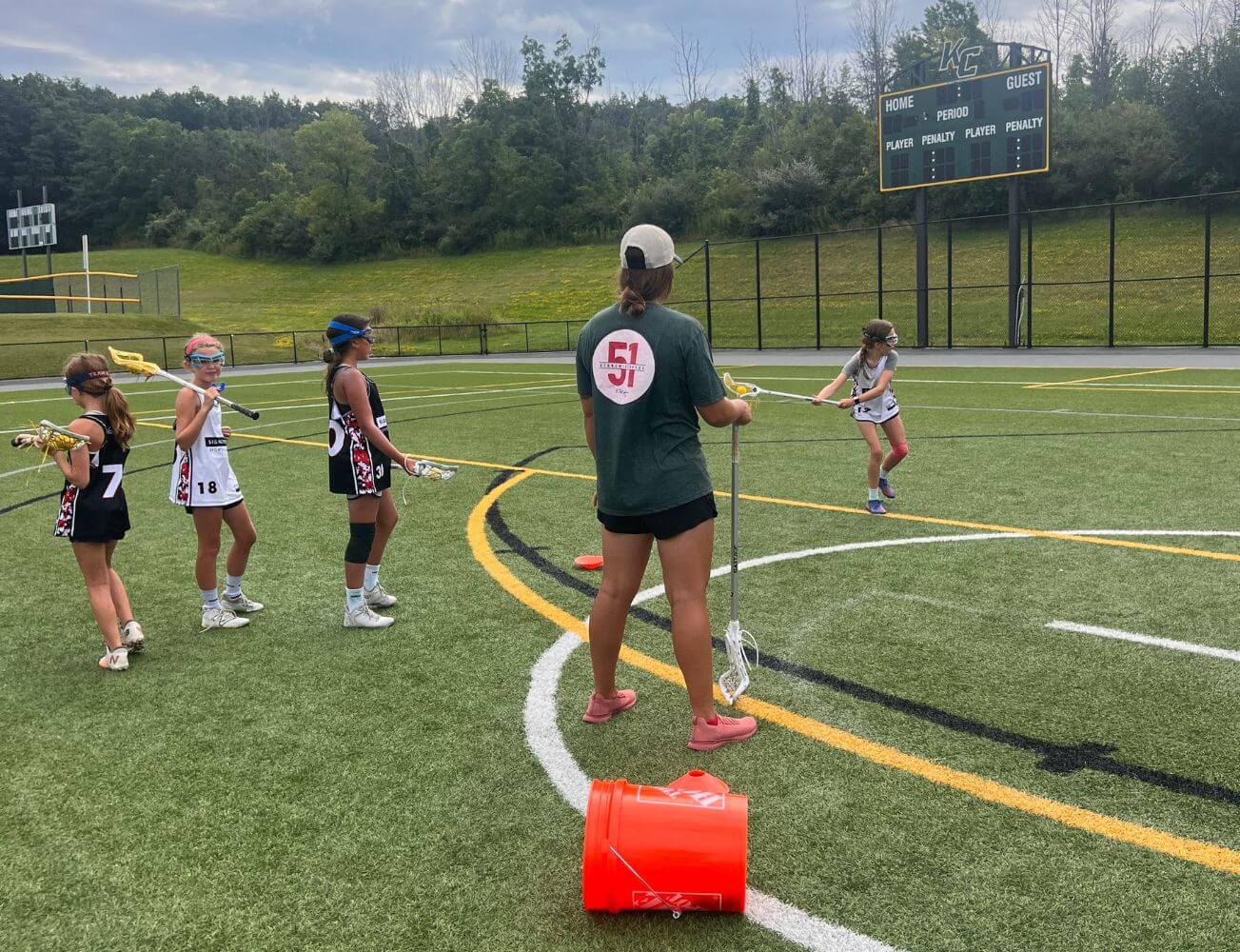 Young lacrosse players practicing drills with a summer sports camp coach