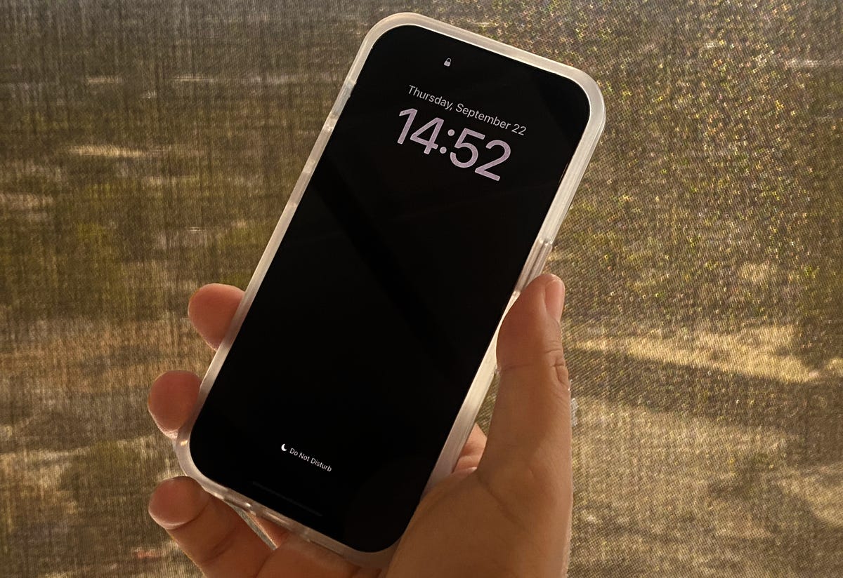 An iPhone 14 Pro with a black screen that shows the time and date