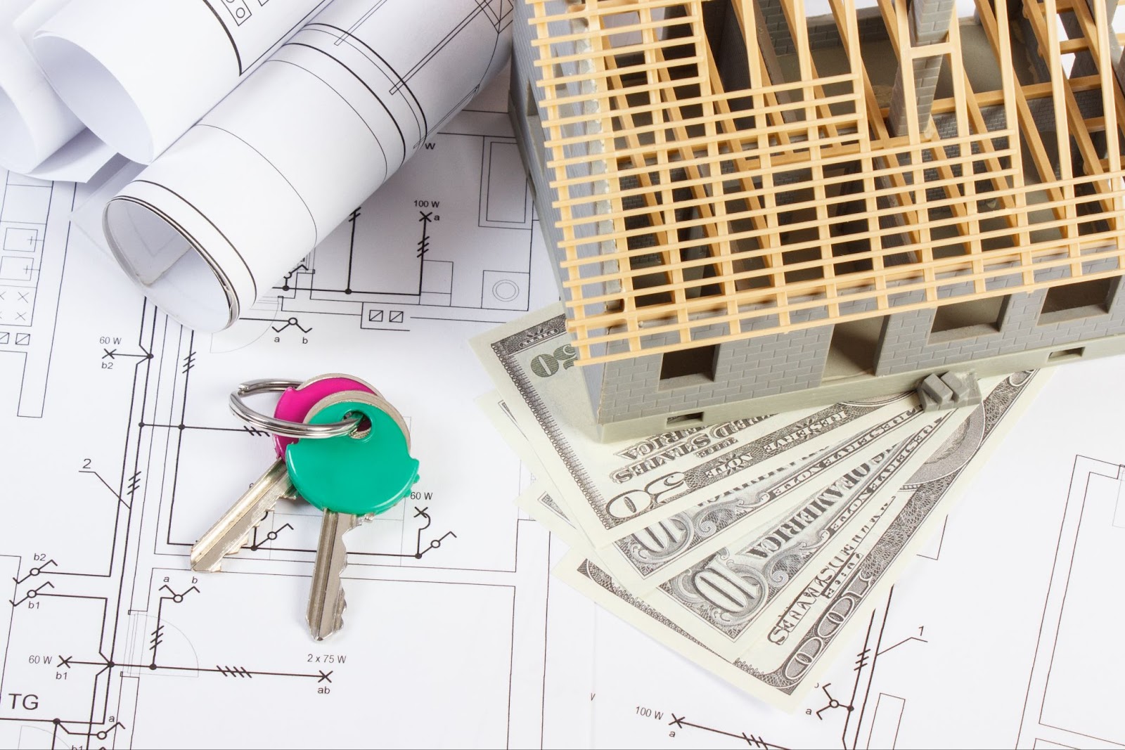 An image of a construction project working with  electrical drawings and diagrams for home keys and dollar currencies, symbolizing the cost of building a tiny house