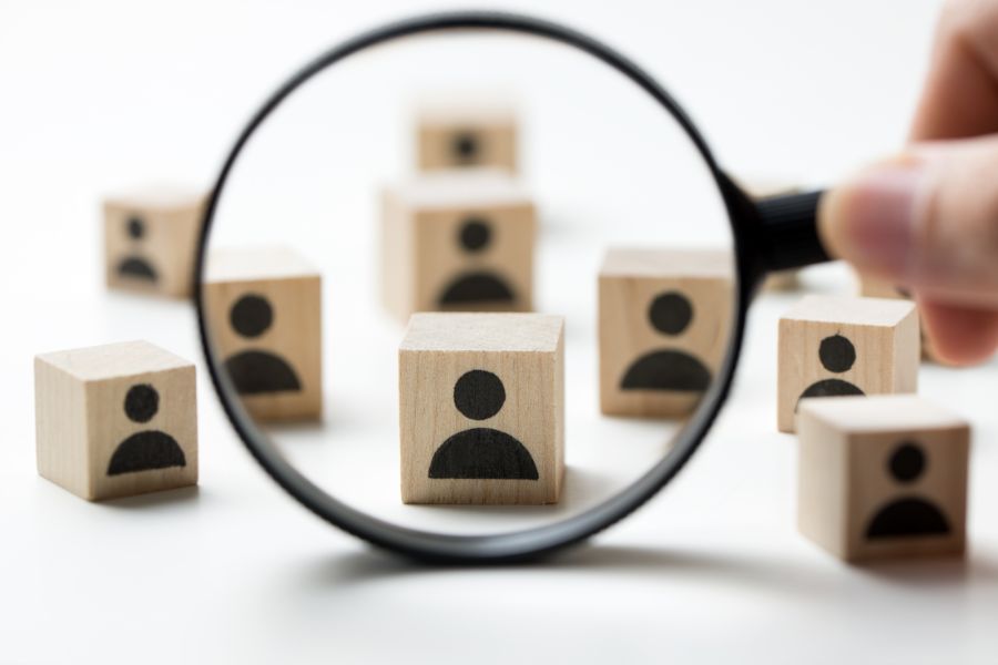 a magnifying glass over wooden cubes with people icons