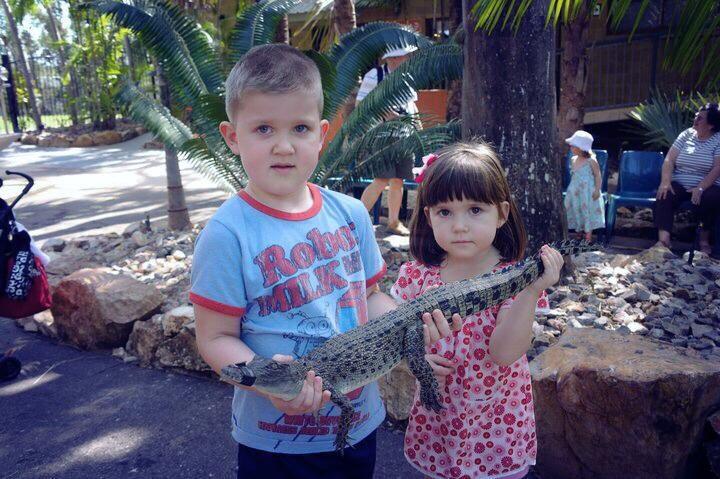 two brave kids holding a baby crocodile