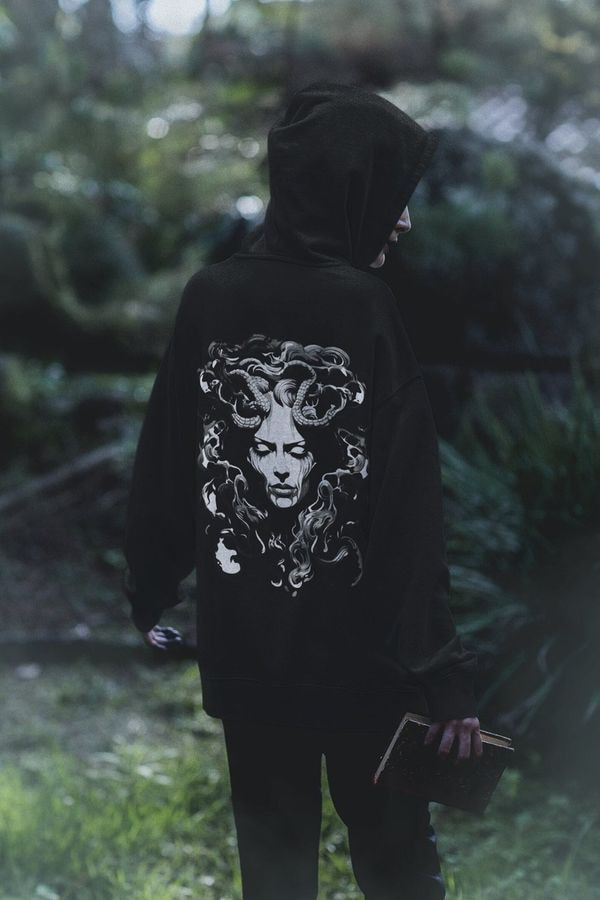 Persona que lleva una sudadera con capucha negra con estampado de Medusa.