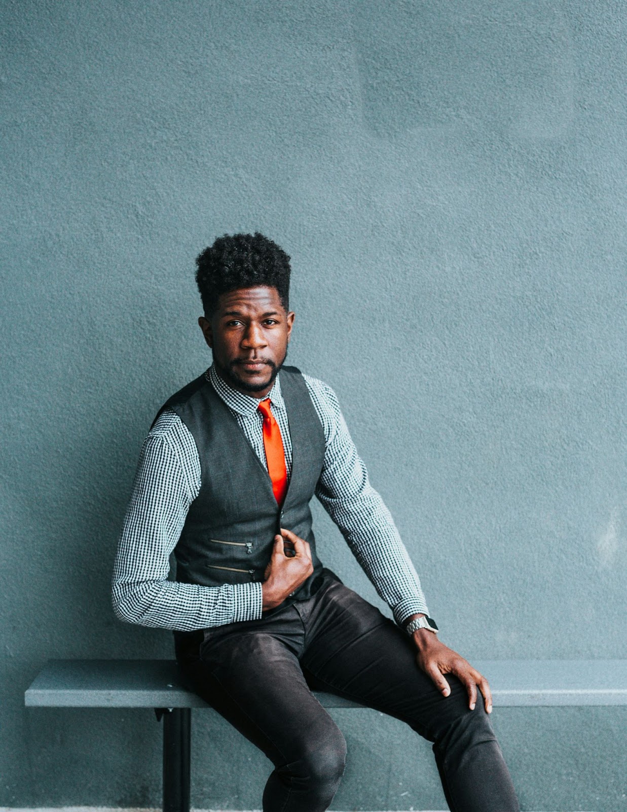 A guy sitting on a bench while giving a confident pose for his modelling headshot