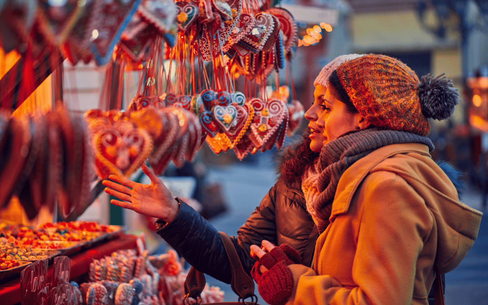 Two women looking at a display of heart shaped ornamentsDescription automatically generated
