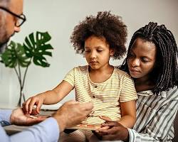 parent and child talking to a therapist in an office