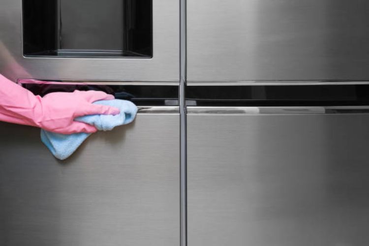 A hand carefully cleaning the commercial refrigerator.