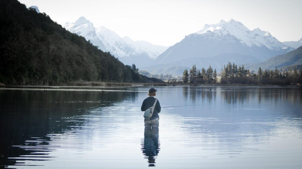 a man standing in the water holding a fish