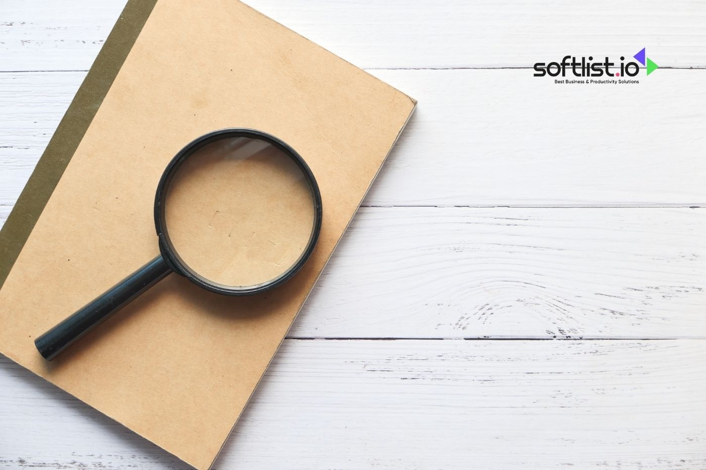 Magnifying glass on a notebook with softlist.io logo on white wooden background.