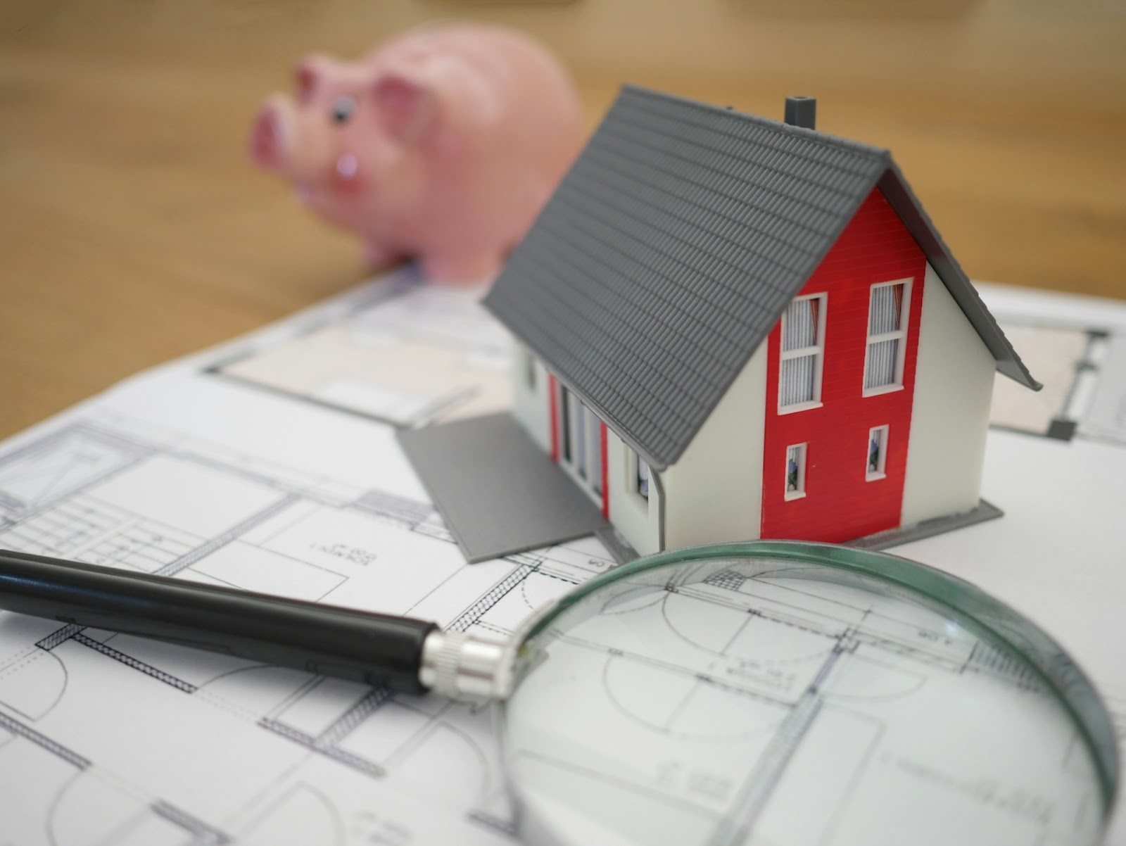 a magnifying glass, house model, and piggy bank
