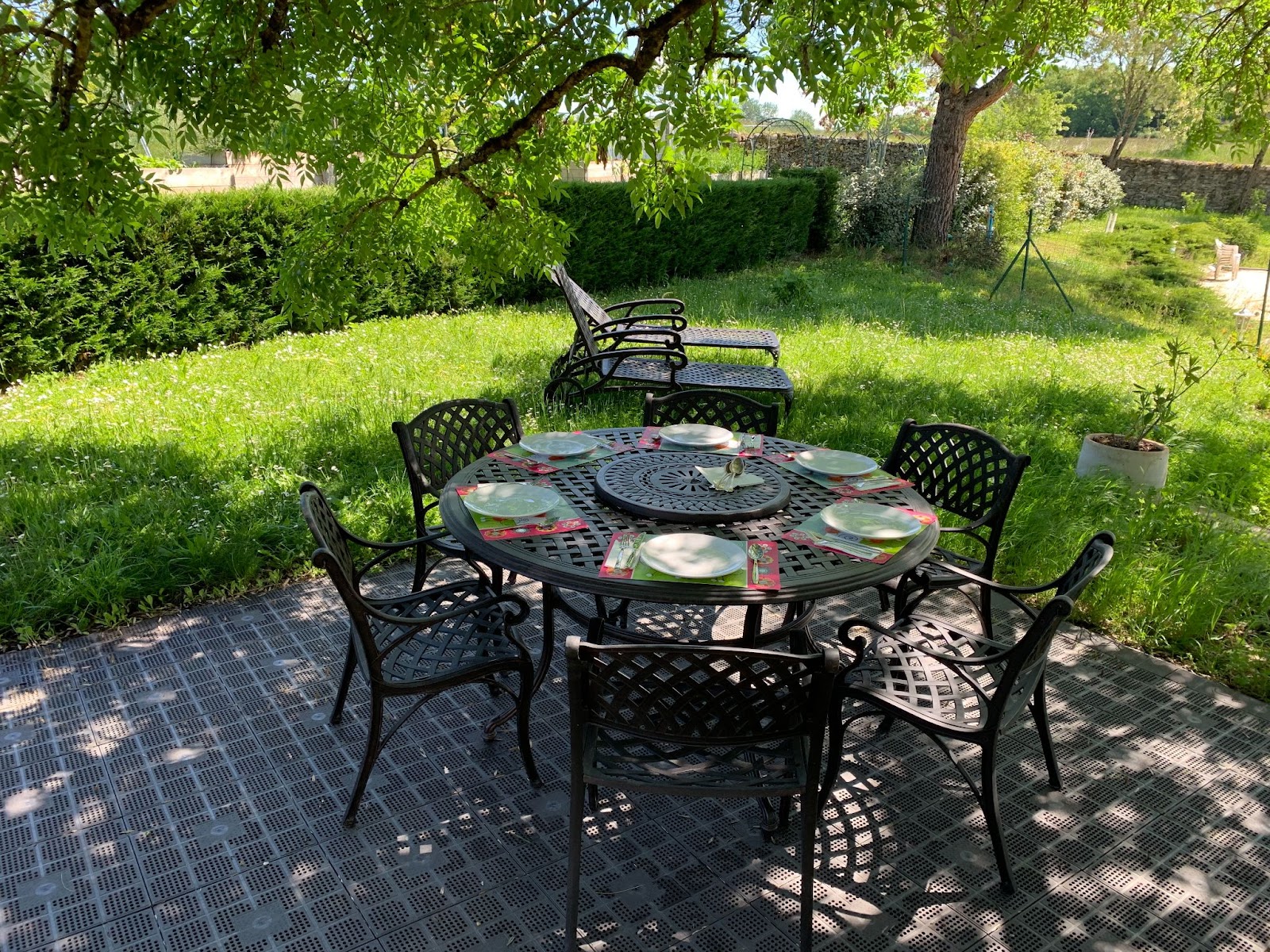 Gedeckter, runder Gartentisch für Pärchenabend mit Sonnenliegen und Drehplatte