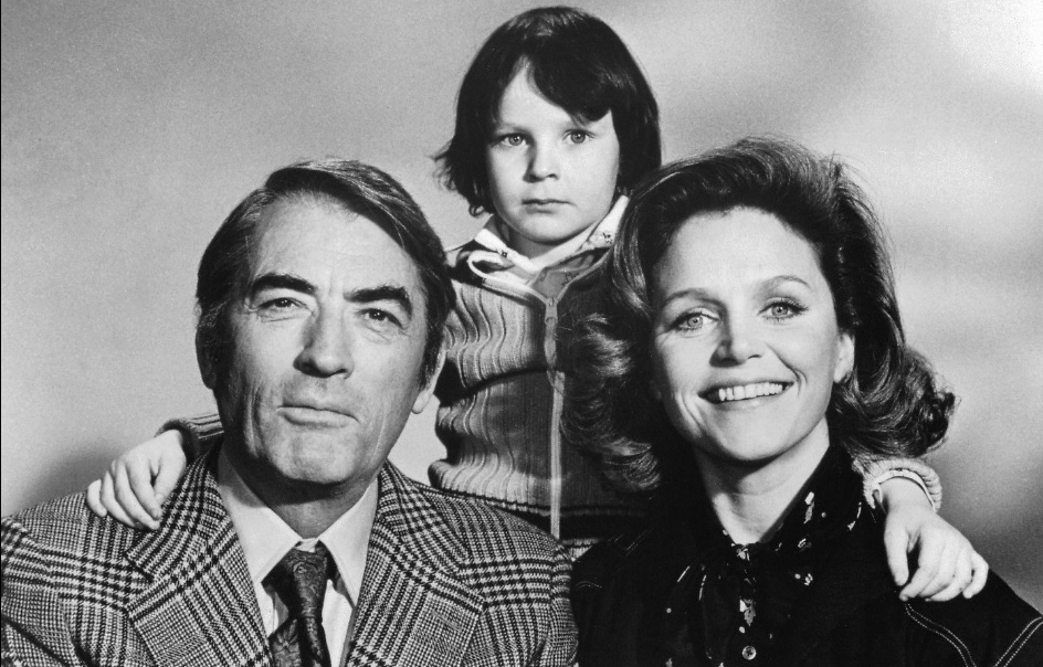 Damien Thorn junto a sus padres en una fotografía blanco y negro. La mirada del niño es perturbadora en La Profecía (1976).