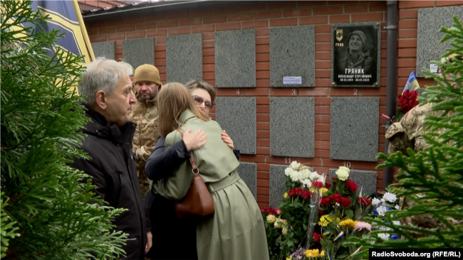 Батьки Олександра Гряника приймають співчуття після поховання урни з прахом сина у колумбарній стіні на Лук'янівському кладовищі у Києві. 28 жовтня 2023 року