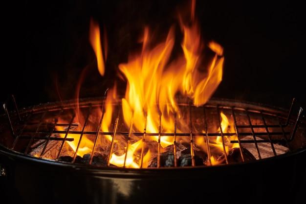 Free photo grill background. barbecue fire grill close-up, isolated on black background