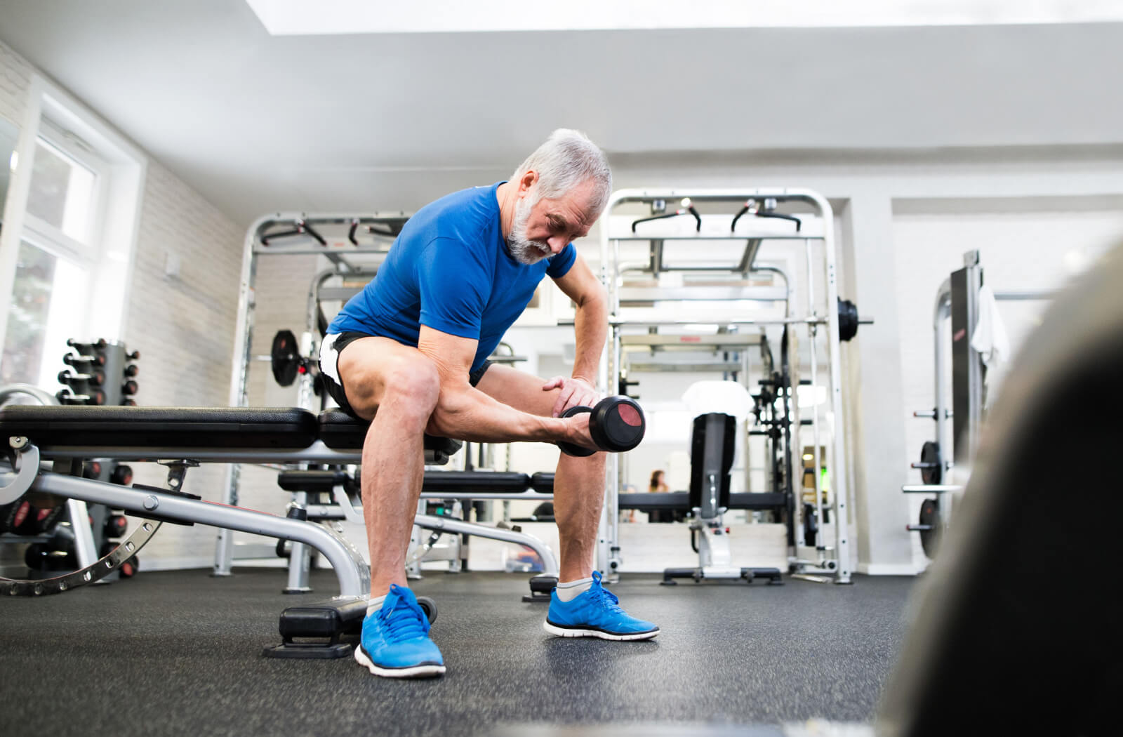 An older adult man exercising using dumbells in an independent living gym.