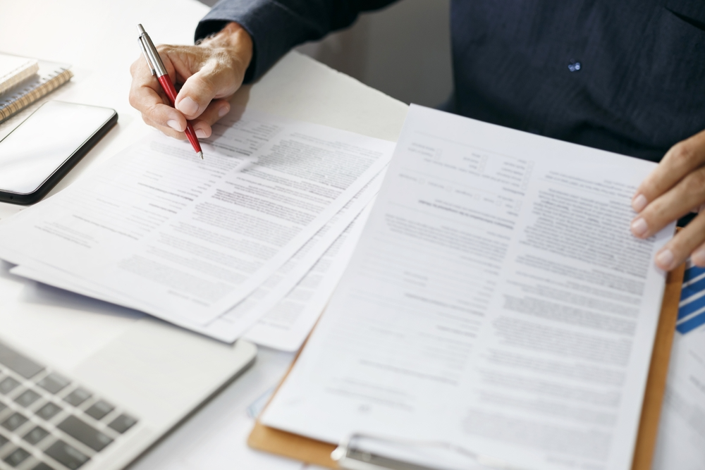 A manager looks at a corrective action audit checklist on a desk.