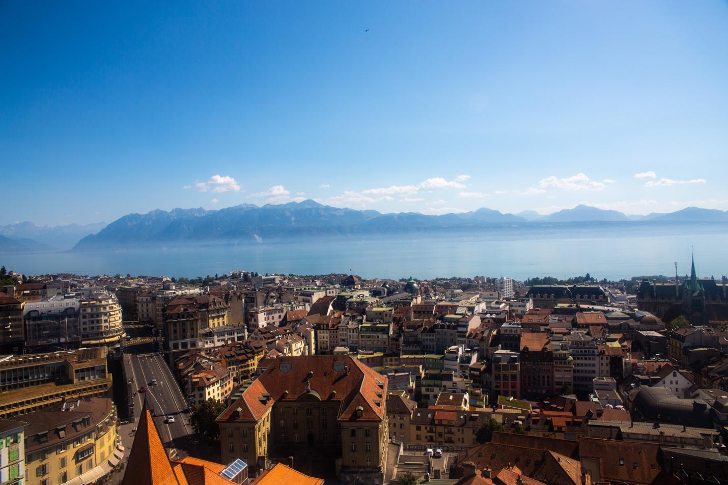 A city with red roofs and a body of water

Description automatically generated