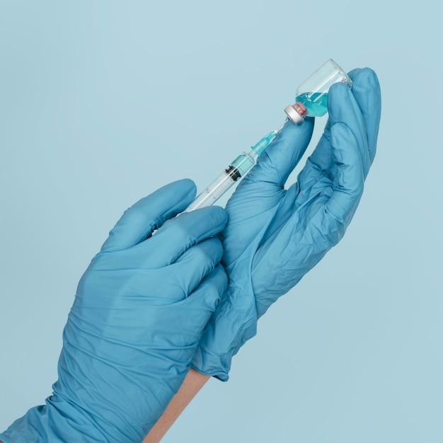 Hands with gloves holding vaccine and syringe