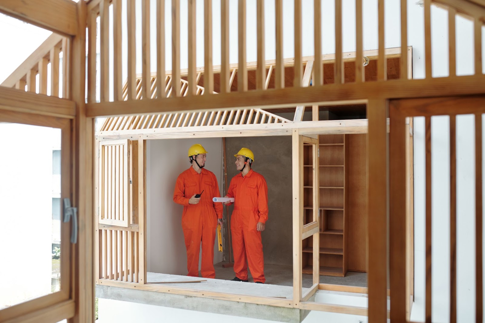  Two contractors with orange suits smiling on a construction site.