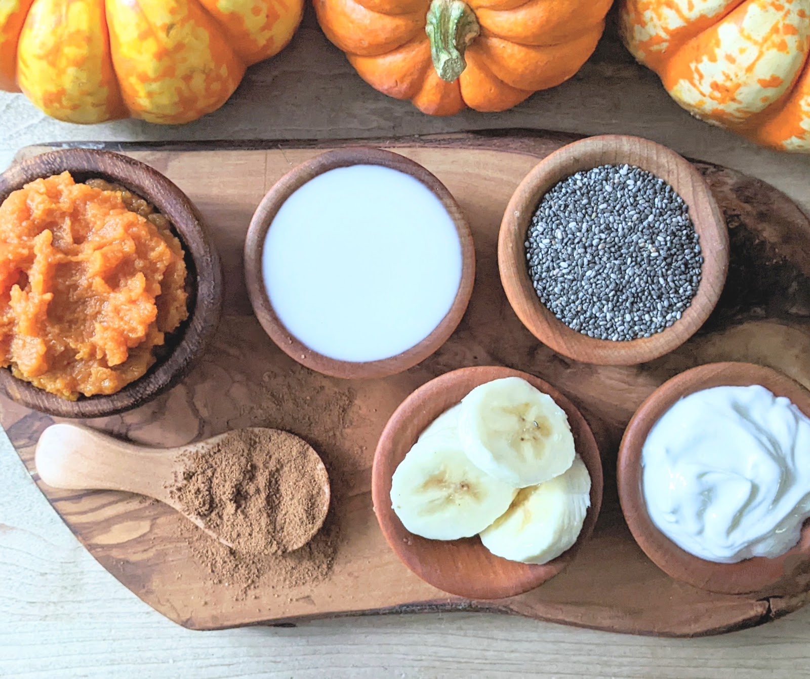top down view of ingredients needed to make this recipe including chia seeds, milk, yogurt, banana, pumpkin and spices